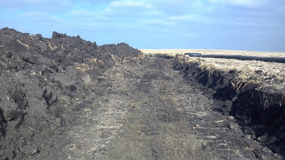 Excavator demolishing an old farm building near Storm Lake, Iowa